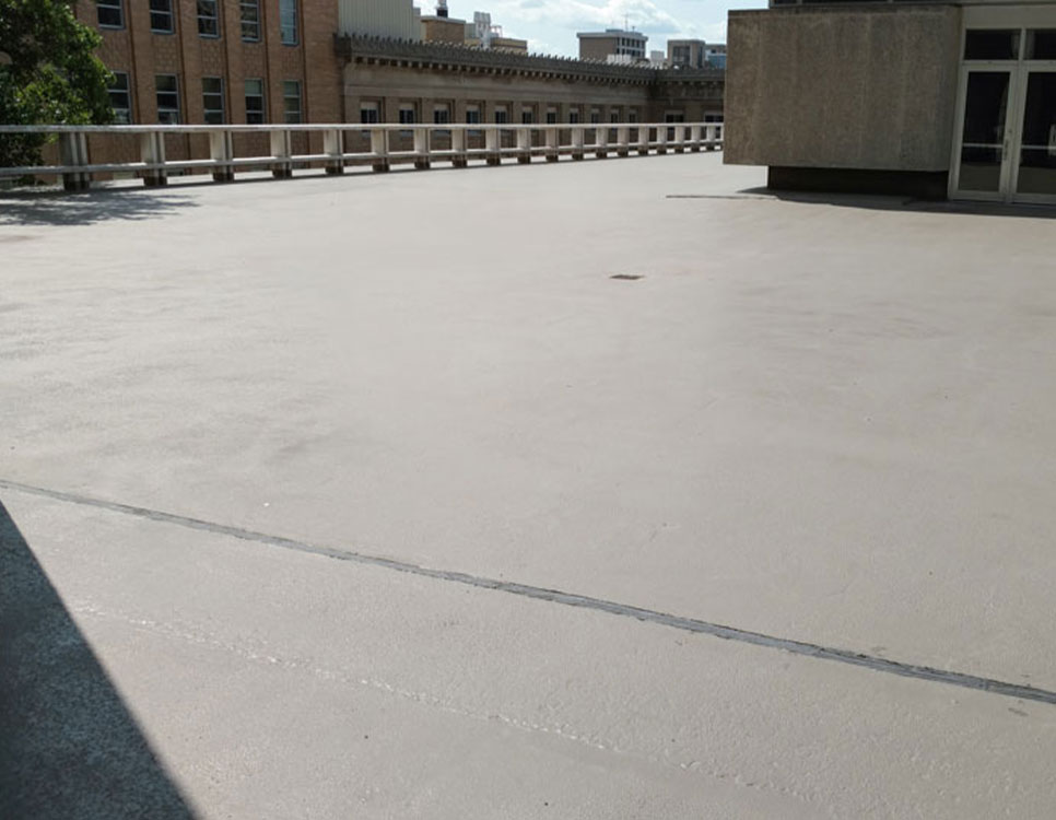 Outdoor Coatings & Sealants on a smooth rooftop surface with protective sealant finish, surrounded by railings and adjacent building structures.