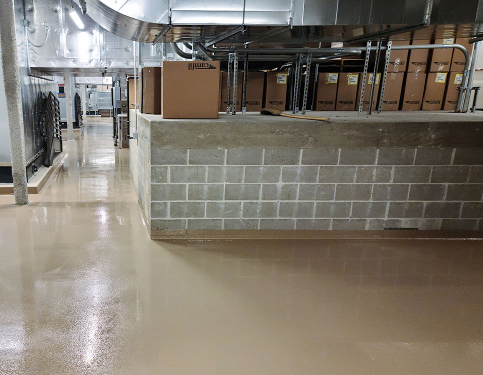 Outdoor Coatings & Sealants applied to a smooth, glossy basement floor in an industrial facility, enhancing durability and easy maintenance.